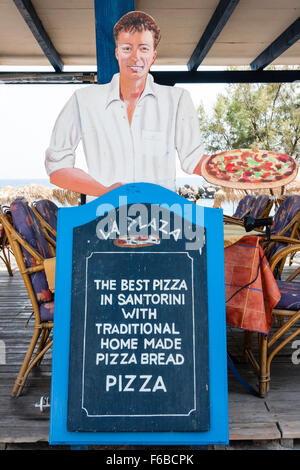 Santorini, Thira. 'La Plaza' restaurant sign. Scheda Menu fatta in casa di pizza e pane con taglio fuori dei maschi di cameriere sorridente holding pizza grande in mano. Foto Stock