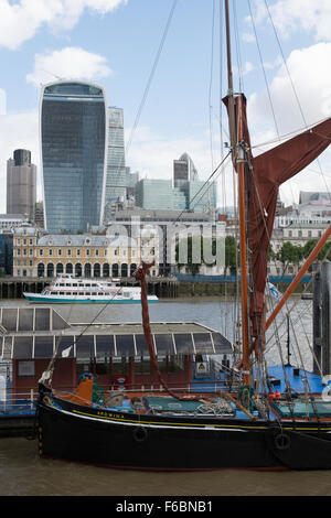 Il restaurato Thames vela Ardwina chiatta ormeggiata nel pool di Londra. Il alti edifici della città di Londra dietro. Foto Stock