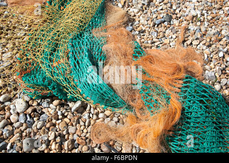 Aggrovigliato e colorati di reti da pesca su una spiaggia ghiaiosa Foto Stock