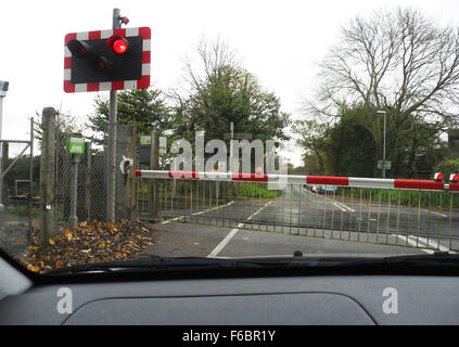 Passaggio a livello ferroviario con i cancelli chiusi e la traversata del treno. Questo è a West Drayton vicino a Chichester in West Sussex Regno Unito Foto Stock