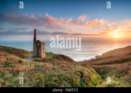 Stunning sunset on the South West Coast Path as it passes the ruins of the Wheal Prosper engine house on cliffs at Rinsey Head n Foto Stock