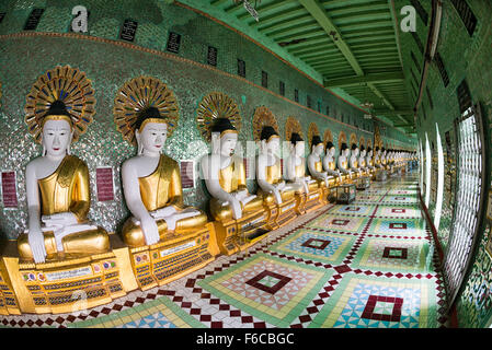 La Pagoda di U min Thonze statue di Buddha Sagaing Myanmar // SAGAING, Myanmar — il colonnato curvo della Pagoda di U min Thonze (nota anche come Pagoda OoHminThoneSel) espone 45 statue di Buddha uniche disposte in una spettacolare formazione a mezzaluna costruita sulla collina di Sagaing. Il nome della pagoda si traduce in "Pagoda delle trenta grotte", riferendosi ai suoi 30 archi d'ingresso decorati che forniscono l'accesso alla caratteristica struttura artificiale del tempio della grotta. Originariamente fondata dal re Tarabya i tra il 1327-1335 e il periodo del regno di Sagaing, l'attuale struttura risale principalmente al 1847 dopo la ricostruzione Foto Stock