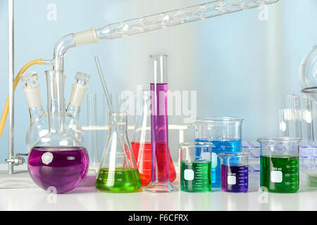 Attrezzature di laboratorio con liquidi colorati su tavolo bianco con finestra in background Foto Stock