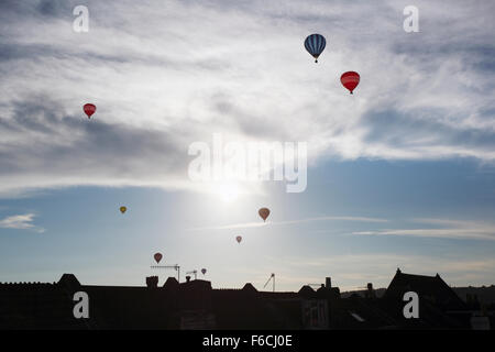 La salita di massa di aria calda Mongolfiere sopra i tetti. Bristol Balloon Fiesta. Regno Unito. Foto Stock