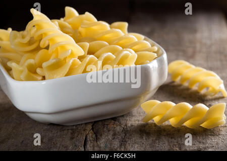 Bollito di fusilli nella ciotola bianco su sfondo di legno Foto Stock