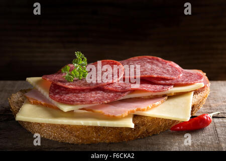 Aprire il panino con prosciutto, salame e formaggio su sfondo di legno Foto Stock