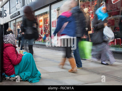 Mendicante dell'Europa orientale, povertà, indigenza, miseria, rovina, disastro, dormiente difficile seduto sul marciapiede fuori Debenhams, Piccadilly, Manchester, Regno Unito Foto Stock
