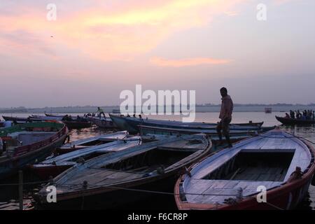 Uomo che cammina attraverso le barche sul fiume Gange Foto Stock