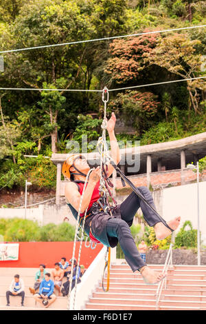 Banos, Ecuador - 23 Maggio 2015: i giovani ispanici esegue guida in pubblico una corda di arrampicata esercizio In Banos Foto Stock