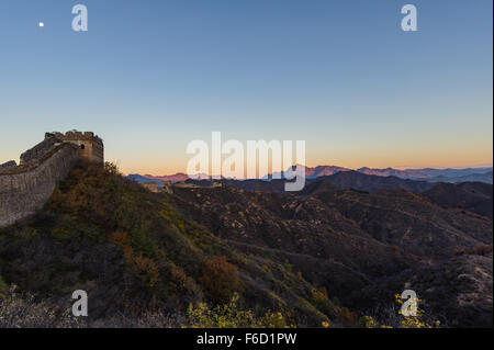 Sunrise presso la Grande Muraglia della Cina come la luna brilla al di sopra di una torre di avvistamento. Preso in autunno. Foto Stock