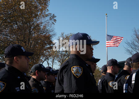 New York, Stati Uniti. Xvi Nov, 2015. Ufficiali della nuova NYPD unità antiterrorismo stand in formazione come noi sventola in background abbassata a metà-personale in onore della Parigi vittime di attacco. Nella scia della Parigi di attentati terroristici, Mayor de Blasio e Commissario NYPD William Bratton ha parlato in occasione di una cerimonia che si terrà su Randall's Island per la distribuzione di una nuova unità antiterrorismo entro la città del dipartimento di polizia, la risposta della critica il comando (CRC). Credito: Albin Lohr-Jones/Pacific Press/Alamy Live News Foto Stock