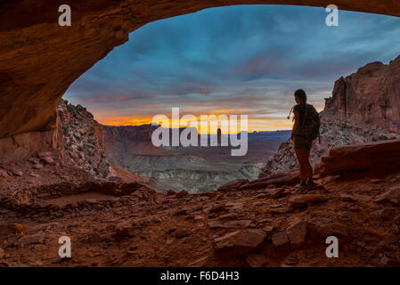 Ragazza Backpacker guardando il bellissimo tramonto dall'interno del falso Kiva il Parco Nazionale di Canyonlands Moab Utah STATI UNITI D'AMERICA Foto Stock