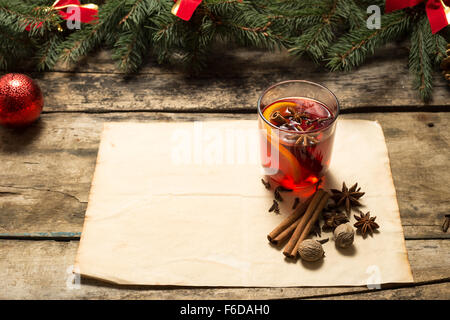 Bicchiere di vin brulé con spezie e albero di natale rami attorno su sfondo di legno Foto Stock