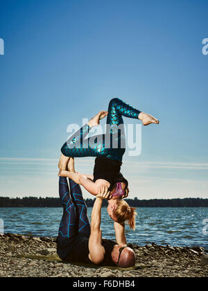 Coppia sportiva formazione acro yoga all'aperto, per la stagione estiva, il mare e il cielo blu Foto Stock