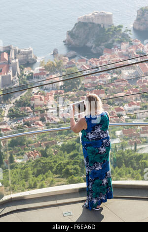 Donna prendendo foto con iPad, Mt Srd lookout, Dubrovnik, Croazia Foto Stock