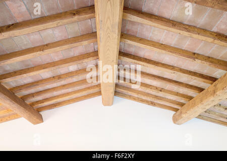 Tradizionale Toscano oak trave di legno sul soffitto di mattoni rossi e modello di parete su sfondo. Classico italiano interni rurale. Foto Stock