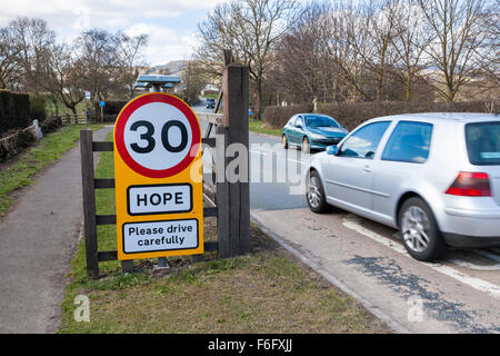 30 km/h il limite massimo di velocità cartello stradale con una richiesta per la preghiamo di guidare con attenzione alla speranza nel Derbyshire, England, Regno Unito Foto Stock