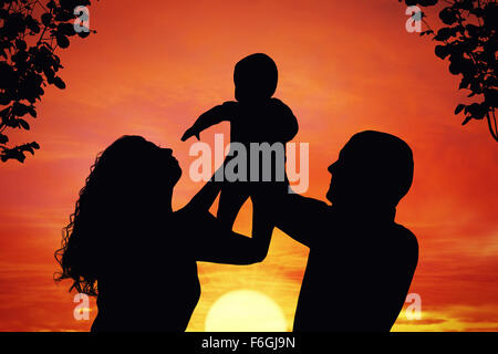 I genitori con il loro bambino al tramonto, sollevamento baby fino nell'aria. Silhouette di una famiglia felice di tre persone Foto Stock