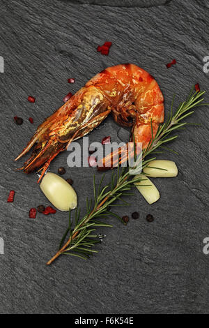 Intero grigliato Gambero gigante con il rosmarino, lâ aglio e il peperoncino rosso su nero ardesia sfondo. Foto Stock