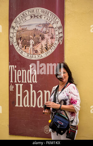 I turisti con la fotocamera davanti a un negozio di sigari e tabacco manifesti davanti a un sigaro cubano business, manifesti pubblicitari, Foto Stock