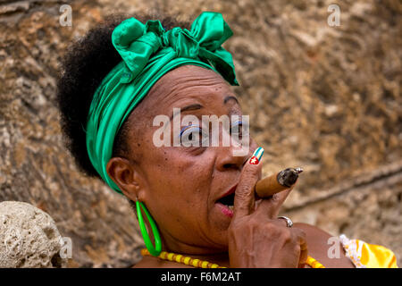 Vecchio pesantemente fatto donna cubana con i capelli verdi bow di fumare un sigaro Havana, sigaro cubano con le unghie laccate con bandiera cubana, Foto Stock