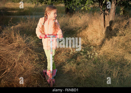 Bella ragazza scooter di guida su strada rurale outdoor in natura Foto Stock