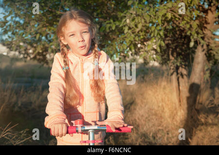 Bella ragazza scooter di guida su strada rurale outdoor in natura Foto Stock