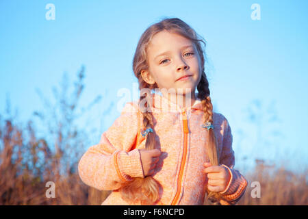 Ritratto di una ragazza con pig-tail su una soleggiata giornata all'aperto Foto Stock