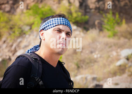 Un uomo in una t-shirt e una bandana sulla natura in una giornata di sole Foto Stock