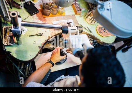 Gioielliere lavorando su metalli con dispositivo ottico che consente per lavori di precisione Foto Stock