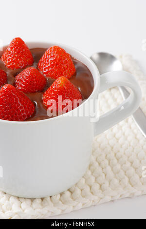 La tazza di fragole in budino di cioccolato su bianco tabella mat Foto Stock