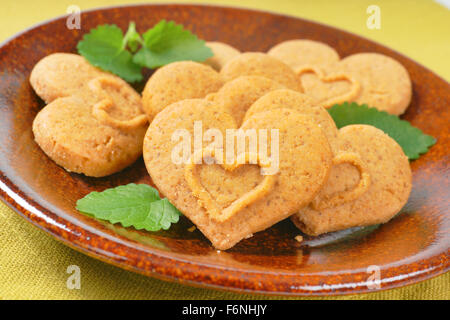 Dettaglio di heart-shaped cookies e menta sulla piastra marrone Foto Stock