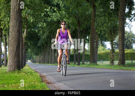 Donna in Bicicletta Escursioni in bicicletta attraverso il paesaggio rurale in estate Foto Stock