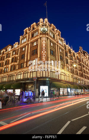 I famosi magazzini Harrods illuminata di notte con auto luci di passaggio a Londra Foto Stock