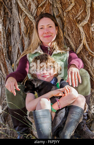 Attraente madre e figlio giovane posano con cani per le fotografie di tree sul ranch Foto Stock