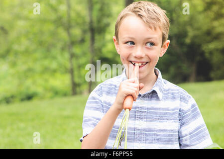 Ragazzo caucasico carota per mangiare all'aperto Foto Stock