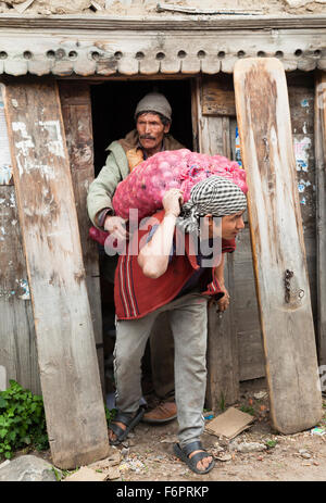 Indian operaio che trasportano le verdure in un villaggio himalayano di Himachal Pradesh. Foto Stock