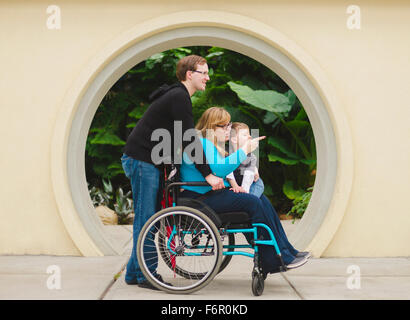 Uomo paraplegico di spinta moglie e figlio Foto Stock