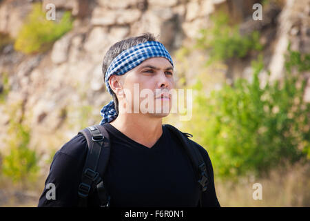 Un uomo in una t-shirt e una bandana sulla natura in una giornata di sole Foto Stock