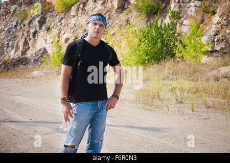 L'uomo in montagna con uno zaino e una bottiglia di acqua in una calda giornata di sole Foto Stock