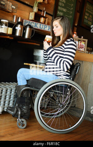 Donna paraplegico in sedia a rotelle di bere il caffè Foto Stock