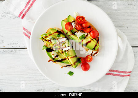 Toast con avocado e pomodori su piastra Foto Stock