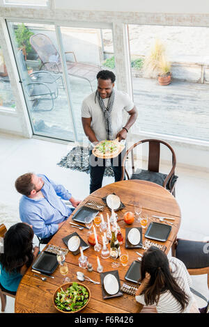 Uomo che serve agli amici a cena Foto Stock