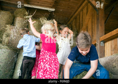 Gruppo di bambini in riproduzione stabile con fieno Foto Stock