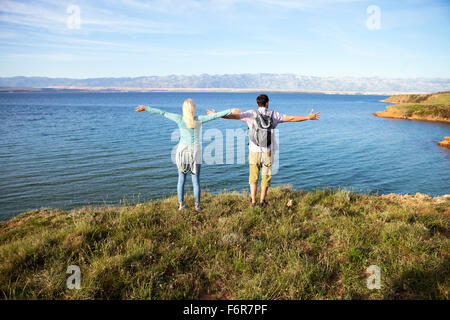 Coppia giovane permanente sulla scogliera braccia tese Foto Stock