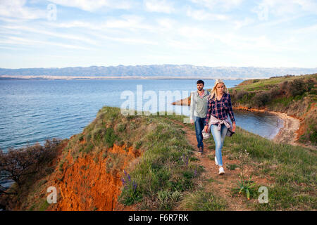 Coppia giovane escursioni a piedi lungo il sentiero costiero Foto Stock