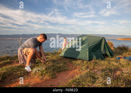 Coppia giovane edificazione tenda sul bordo d'acqua Foto Stock