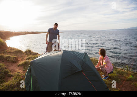 Coppia giovane edificazione tenda sul bordo d'acqua Foto Stock