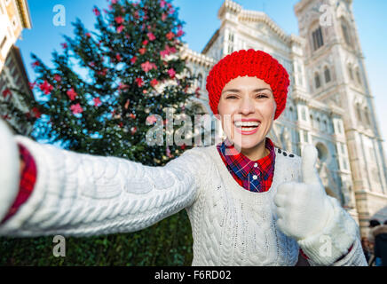 Pollice su per il Natale a Firenze !! Felice giovane donna tourist rendendo selfie nella parte anteriore del tradizionale albero di natale vicino al Duomo ho Foto Stock