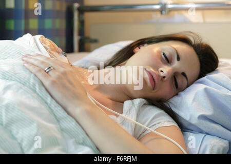 Malati giovane donna posa nel letto di ospedale con catetere venoso centrale (CVC) essendo somministrati fluidi e la nutrizione per via parenterale (PN) modello di rilascio: Sì. Proprietà di rilascio: No. Foto Stock